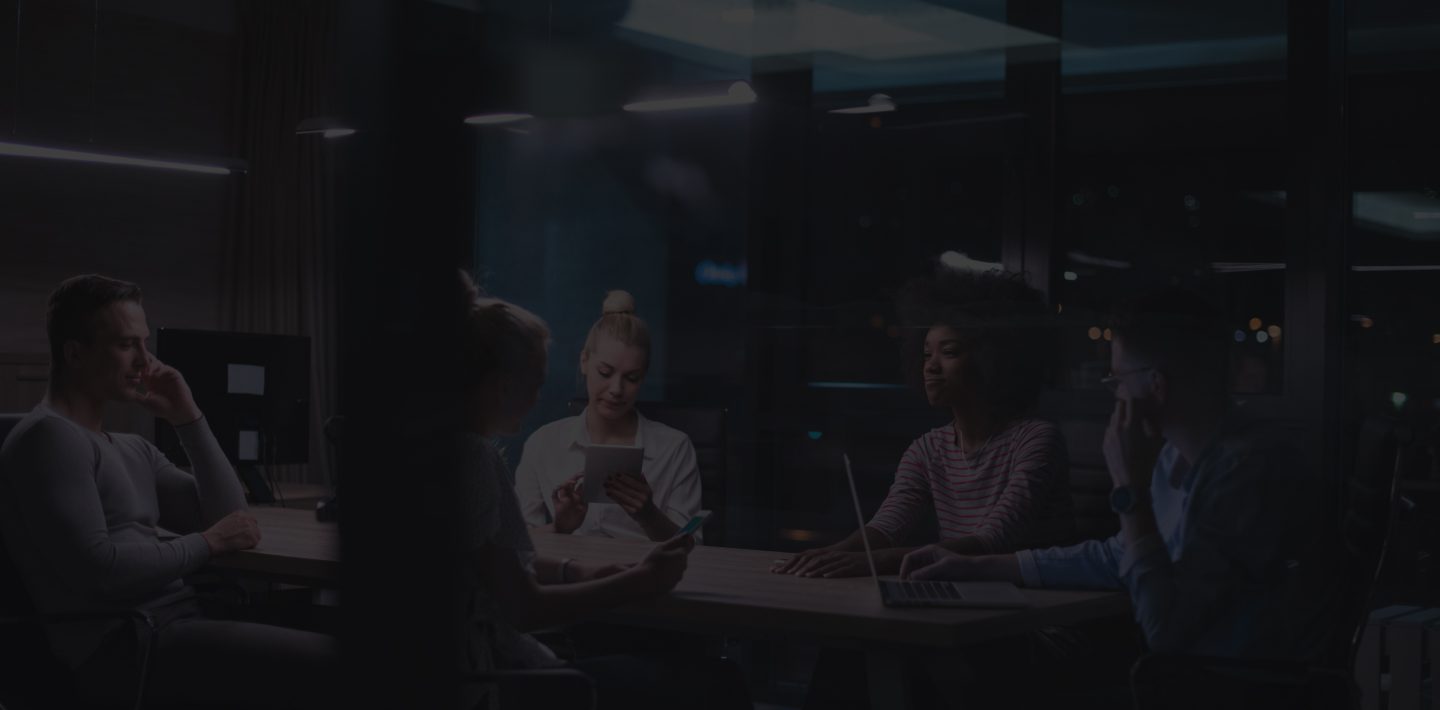 A Group of People in a Dimly Lit Room Engaged in a Discussion or Meeting.