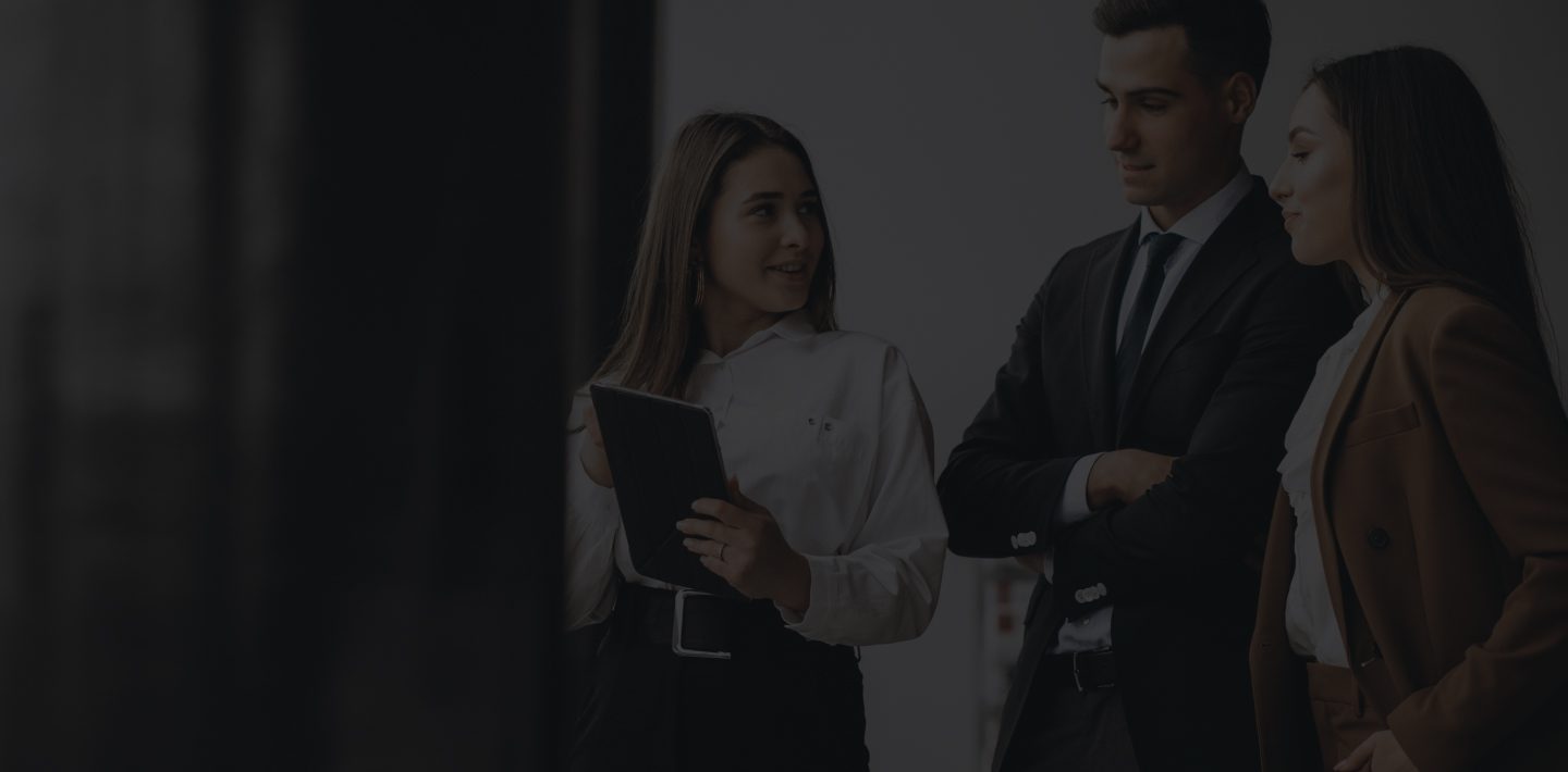 Two Women and A Man in Professional Attire Standing in A Corporate Setting.