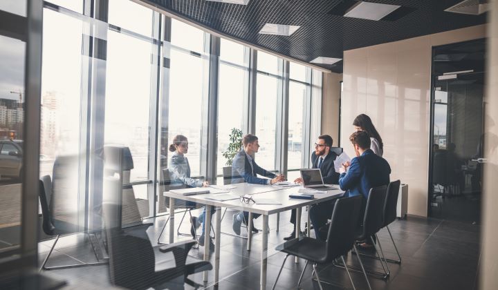 A Group of Five Corporate Professionals Discussing Something While Sitting Around A Conference Table.
