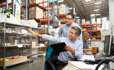 An Indoor Warehouse Scene With Stocked Shelves and Three Individuals Working in Inventory Management.