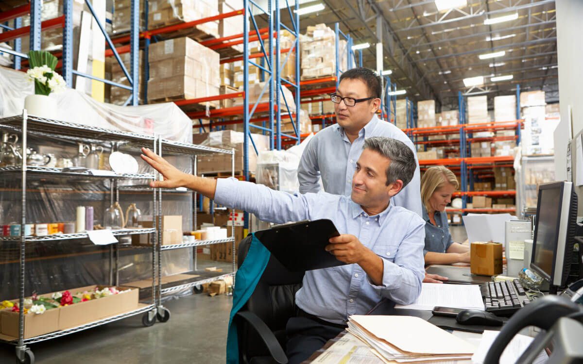 An Indoor Warehouse Scene With Stocked Shelves and Three Individuals Working in Inventory Management.