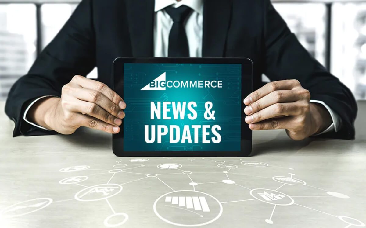 A Man Holding a Tablet Displaying 'Bigcommerce News & Updates' With Icons Drawn on the Table.