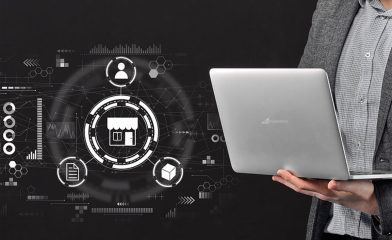 A Person in a Gray Blazer Holding an Open Laptop Alongside A Digital Overlay of Various White Icons and Graphics Related to BigCommerce Integration.