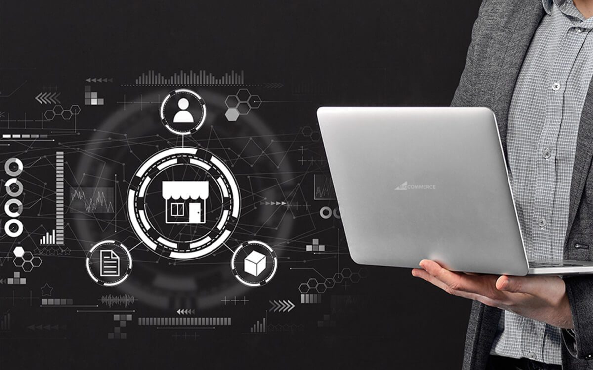 A Person in a Gray Blazer Holding an Open Laptop Alongside A Digital Overlay of Various White Icons and Graphics Related to BigCommerce Integration.