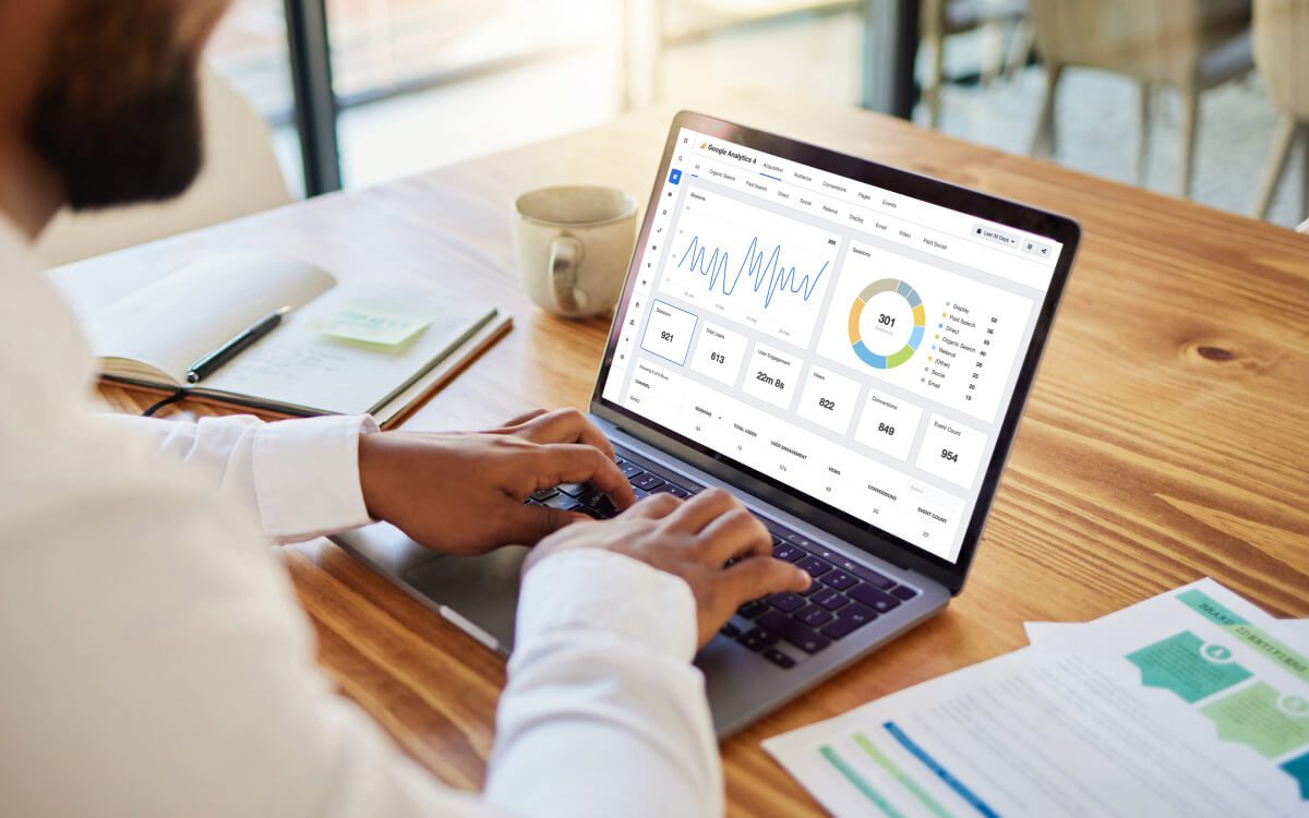 A Person Analyzing Data on a Laptop at a Wooden Desk.