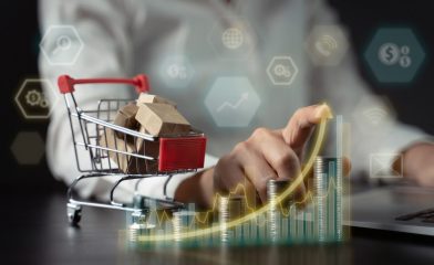 A Person in a White Shirt Interacts With a Digital Interface & A Miniature Shopping Cart Showing Rising and Falling Bar Graphs.
