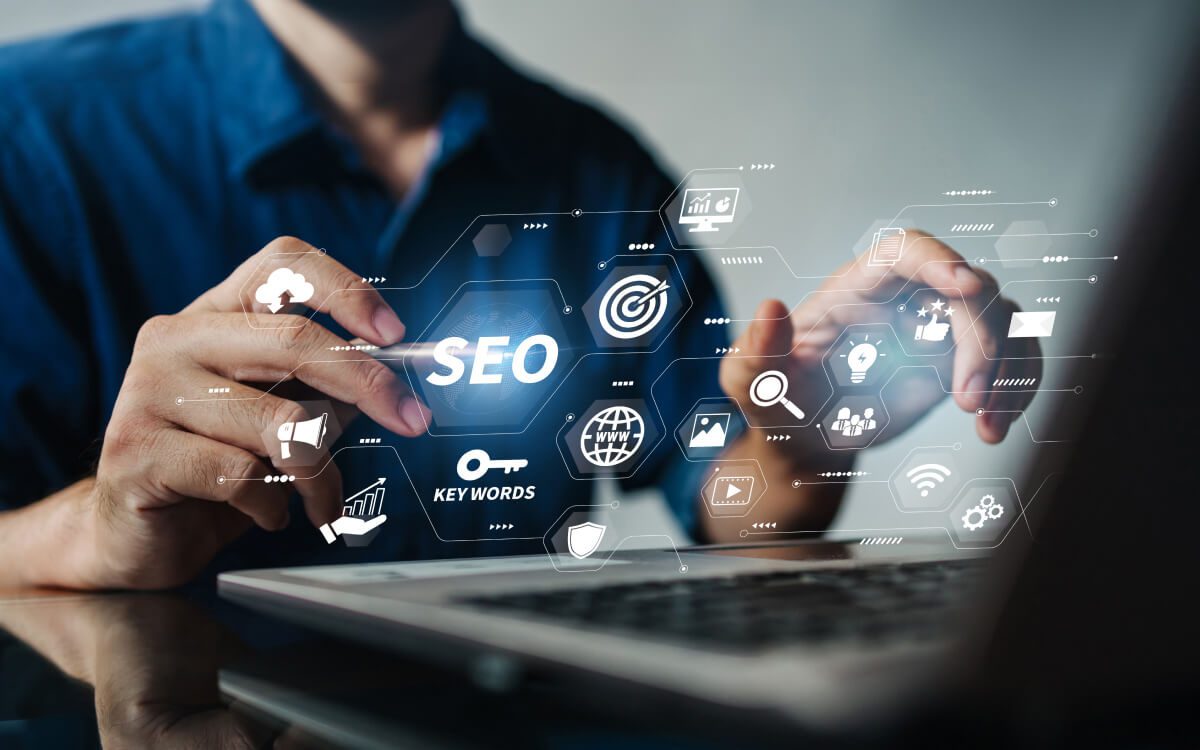 A Person Using a Laptop With Graphics of Various Digital Marketing and Search Engine Optimization (SEO) Icons Floating Above the Screen.