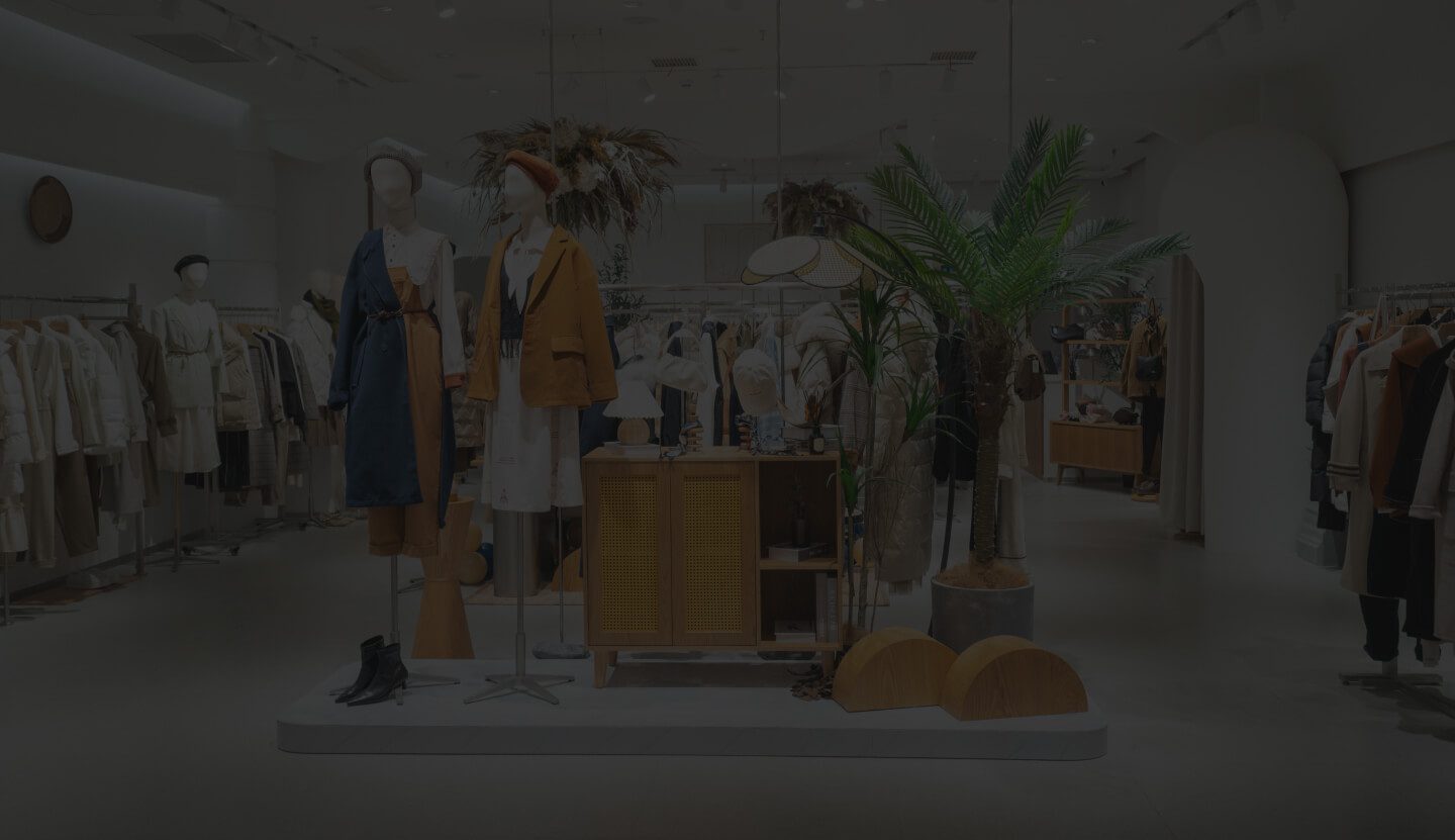 A Modern Clothing Store Interior Showcasing Mannequins Dressed in Fashionable Attire, Surrounded by a Variety of Clothes on Racks, Decorative Plants, and Elegant Lighting.