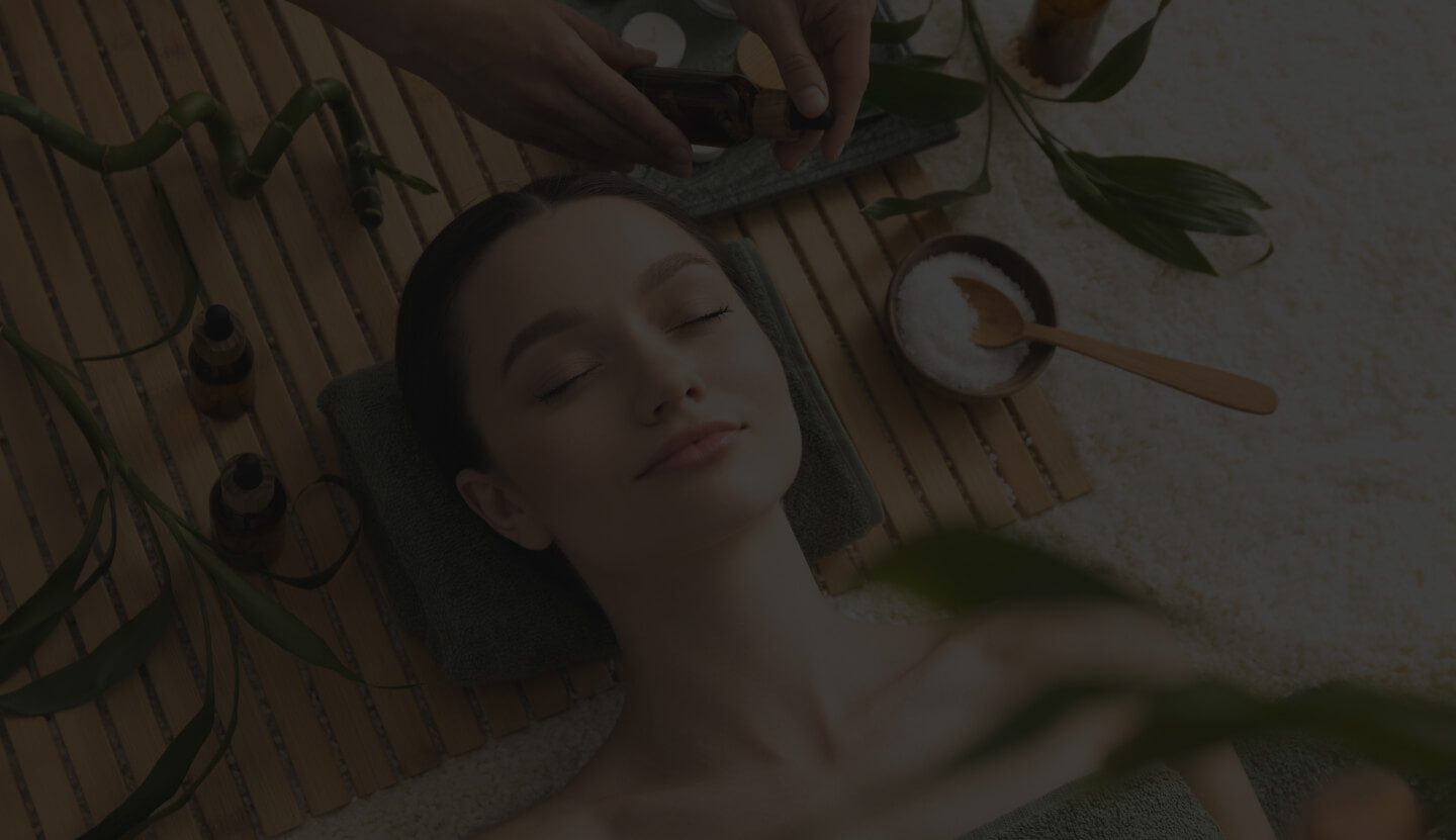 A Woman Receiving a Treatment in A Serene Spa Environment. The Scene Features Bamboo Decor, Green Leaves, and Essential Oils.