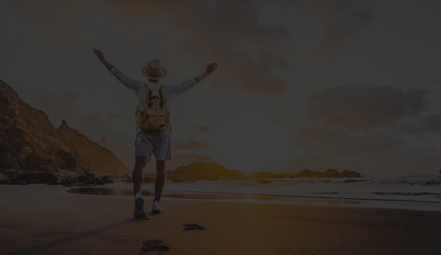 Person Standing on a Beach at Sunset With Arms Outstretched.