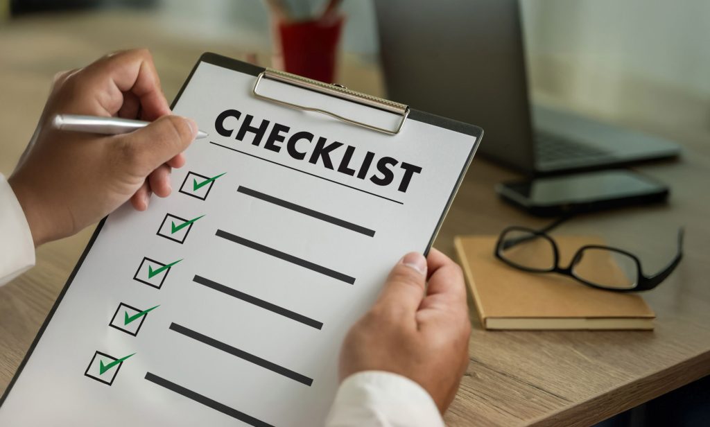 Hand holding a completed checklist clipboard.