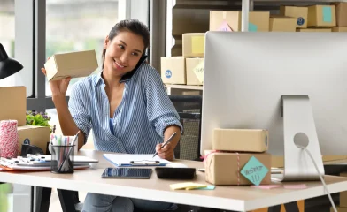 Woman multitasking at her desk with packages.