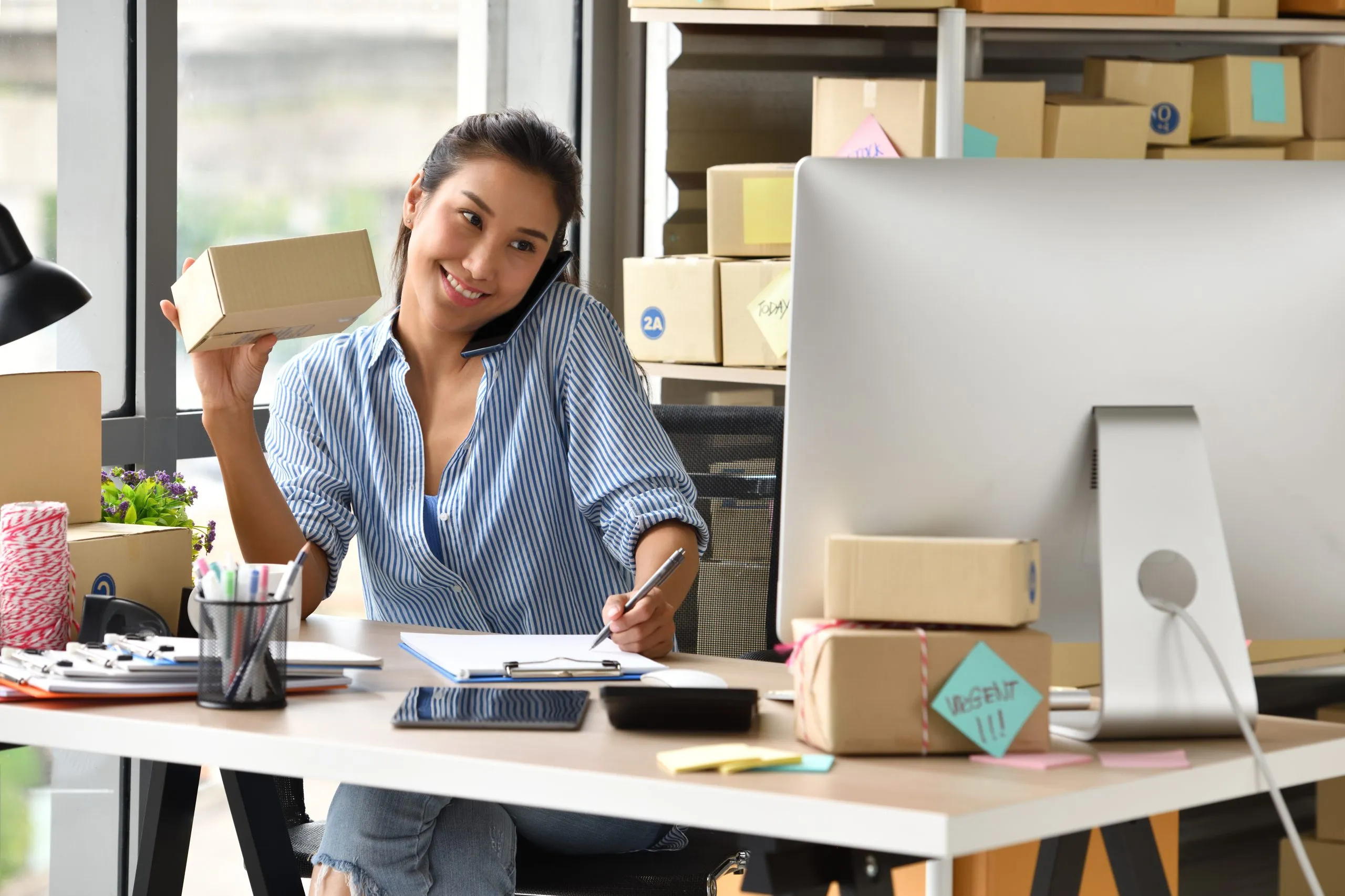 Woman multitasking at her desk with packages.