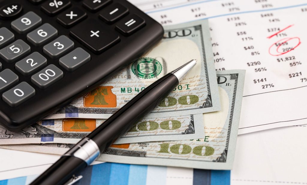 Calculator and pen on US currency bills.