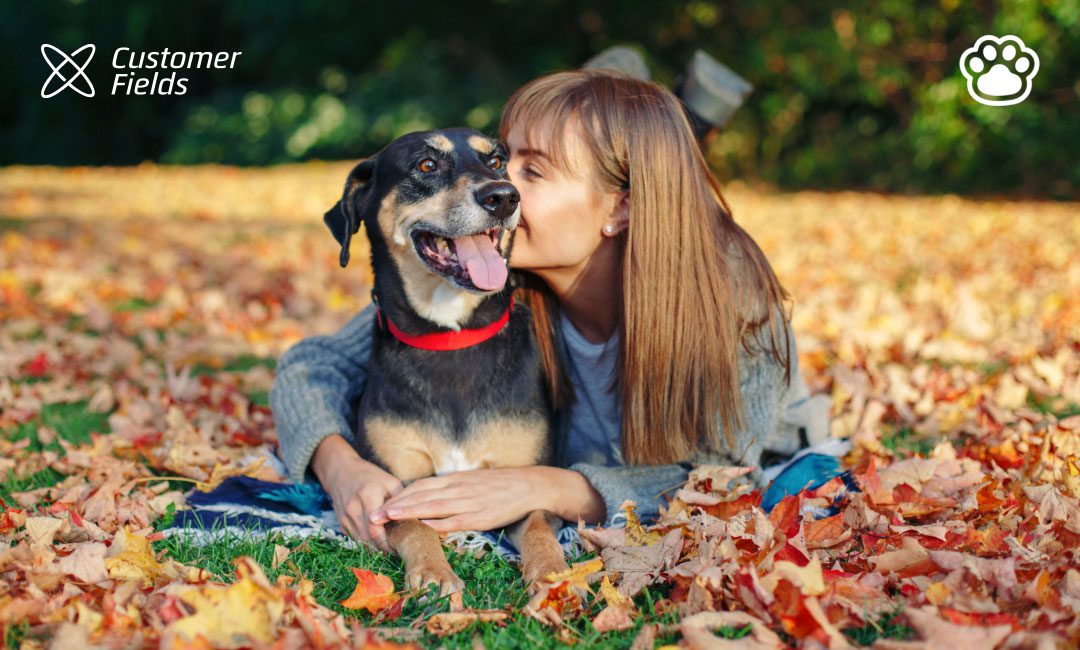 After downloading the customer fields app, a woman and her dog play in autumn scenery.