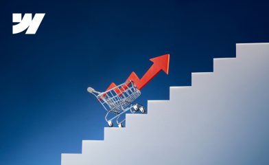 A shopping cart with a red upward arrow climbs stairs, symbolizing eCommerce growth & Webflow development services, with the Webflow logo in the corner.