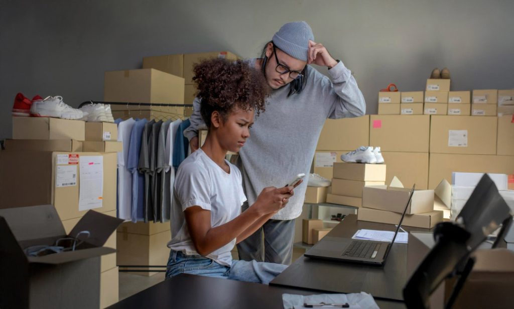 Inventory management scene with colleagues collaborating over a laptop and documents.