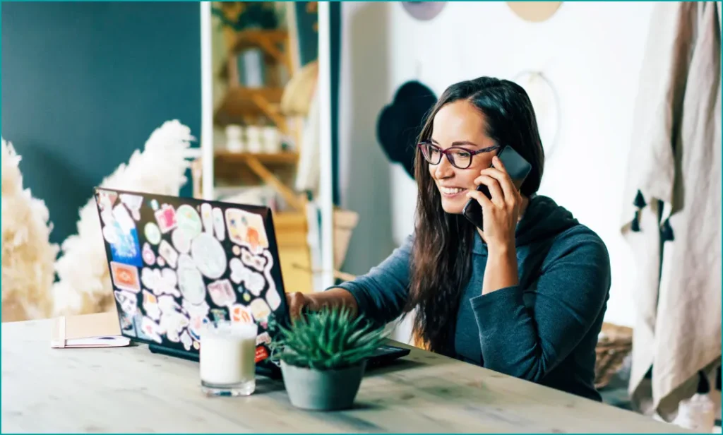 A Woman Working On an SEO Strategy on Her Laptop While Talking on the Phone in a Modern Workspace.
