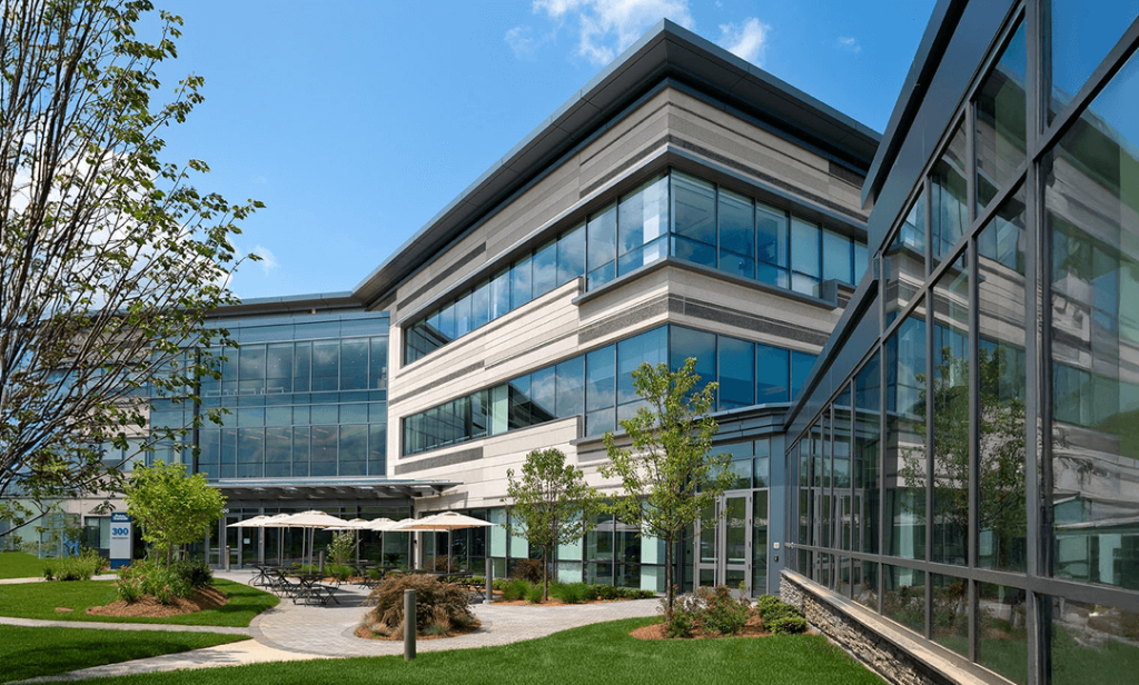 The exterior of a modern Boston Scientific office building with large glass windows & landscaped greenery