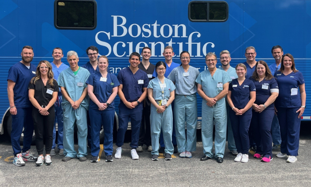 Boston Scientific employees in scrubs & work attire standing together outside a branded mobile lab.