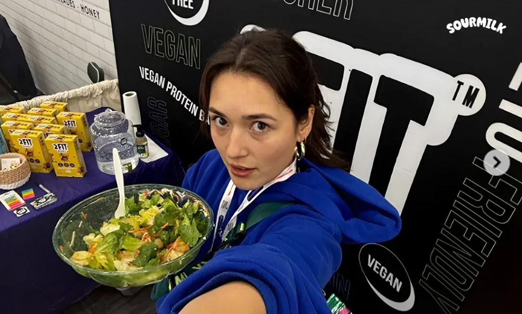 Kiki Couchman, co-founder of Sourmilk, holds a large bowl of yogurt salad while standing at a pop-up event booth